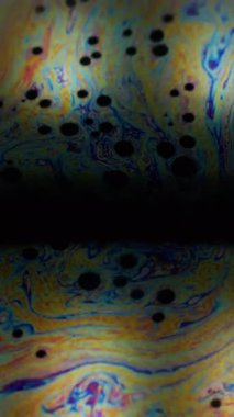 Dikey video. Holografik girdap. Mürekkep karışımı. Renkli boya sıvısı akıyor. Soyut küre bulanık lens arkaplan merkezi boş alan çerçevesi.