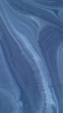 Dikey video. Akrilik pigment. Dalgalı mürekkep. Odaklanmamış mavi renkli mermer doku ıslak lekeler su parçacıkları soyut sanat arka planına dökülüyor.