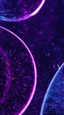 Dikey video. Bulanık kabarcıklar. Yağ emülsiyonu. Mor mavi neon açık renkli akrilik desenli su yuvarlak sıvı koyu soyut sanat arka planına yayılıyor.