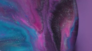 Odaklanmamış mürekkep damlası. Akrilik dökülmesi. Soyut sıvıyı karıştıran mor mavi boya. Işıldayan pigment menekşe arkaplanda çözülüyor.