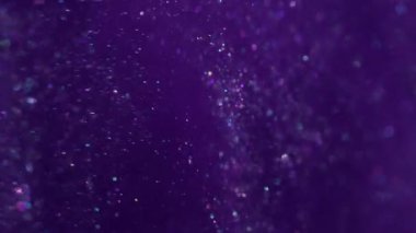Bulanık pullar. Mürekkep sıvısı. Mor parçacıklar suya parlak pigmentler döküyorlar. Parıldayan soyut kozmik bulut patlaması arka planda parlıyor.