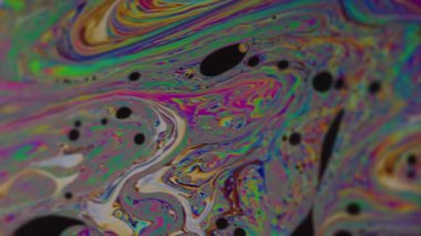Dikey video. Akan kabarcıklar. Mürekkep sıvısı. Bulanık yeşil pembe mor yağ lekeleri soyut koyu siyah arkaplanda yüzen sarı mavi doku.