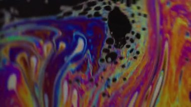 Dikey video. Damlacık yağı. Renk karışımı. Odaklanamayan sarı mor mavi mürekkep su dokusu akan yeşil yuvarlak lekeler soyut sanat arka planına dökülüyor.