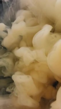 Dikey video. Duman akışı. Soyut mürekkep. Odaklanmamış sarı renkli dumanlı ruhani dokular yaratıcı siyah sanat arka planında sıvı karışımı..