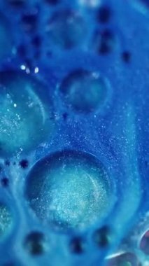 Dikey video. Kozmik ışıltı. Sihirli mavi. Renkli akış sıvısı parıldayan yağ boya dokusu soyut bulanık bokeh ışık sanat arka planında hareket ediyor.