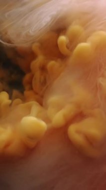 Dikey video. Buhar bulutu. Sıçrama boyası. Odaklanmamış sarı beyaz renk deseni soyut arkaplanda yüzen mürekkep dumanı sıvısı damlası.