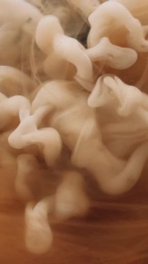 Dikey video. Duman boyası. Buhar bulutu. Soyut sanatın koyu siyah zemininde büyüyen su patlamasında çözünmüş sarı renk sıçrama mürekkebi..