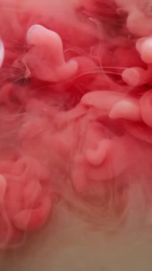 Dikey video. Mürekkep damlası su. Renk sıçraması. Soyut sanat arka planında dönen odaksız pembe beyaz boya dokusu kimyasal bulut sıvısı akışı.