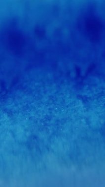 Dikey video. Bulanık mavi. Işıldayan doku. Yanıp sönen kozmik renk parlak su sıvısı soyut modern ışık arka planında hareket ediyor..