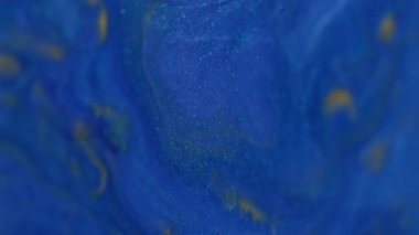 Dikey video. Dökme dokusu. Boya dökülmüş. Soyut sanat arka planında yüzen odaksız mavi renkli parlak sıvı karışımı.