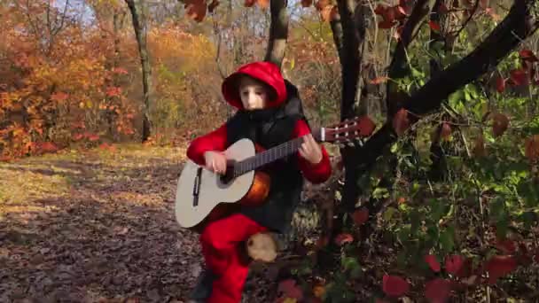 Sonbahar Ormanında Parlak Kırmızı Ağaçların Arka Planında Bir Çocuk Gitarla — Stok video