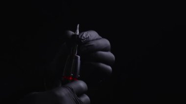 Kalıcı kaş, dudak ve kirpiklerden oluşan siyah steril eldiven ustasının elleri. Makineye kalıcı makyaj için dövme kartuşu yerleştiriyorum.