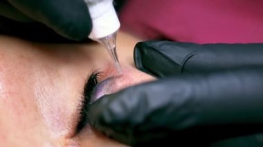 Dövme makinesiyle cilde uygulanan dövme temizleme bileşiminin yakın çekimi. Eski kalıcı göz kapağı makyajının kaldırılması