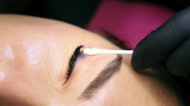 Pamuk çubuğu kullanarak dövme temizleme bileşiminin kalıntılarını temizliyorum. Eski kalıcı göz kapağı makyajının kaldırılması