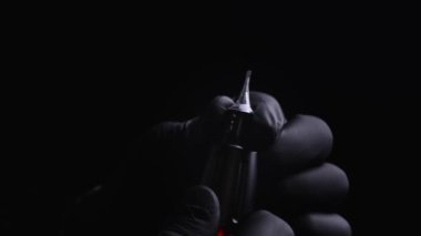 Kalıcı kaş, dudak ve kirpiklerden oluşan siyah steril eldiven ustasının elleri. Bir dövme makinesinin makro çekimi. Üstat, kalıcı makyaj için bir kartuşu çıkartıyor.