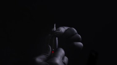 Kalıcı kaş, dudak ve kirpiklerden oluşan siyah steril eldiven ustasının elleri. Ustanın dövme makinesine kalıcı makyaj kartuşunu nasıl yerleştirdiğinin yakın çekimleri.