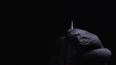 Kalıcı kaş, dudak ve kirpiklerden oluşan siyah steril eldiven ustasının elleri. Dövme makinesinin makro görüntüsü. Üstadı, kalıcı makyaj için bir kartuşun içine yerleştiriyor.