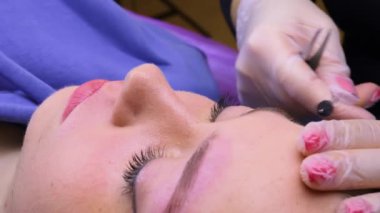 Kalıcı makyaj prosedüründeki kız model kaşları cımbızla hazırlıyor. Kozmetik prosedür kalıcı kaş makyajı. Kaş dövmesi..