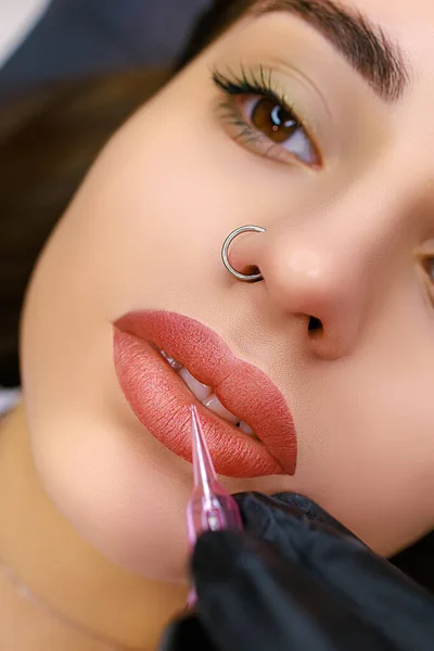 Close-up model\'s lips performed with permanent lip makeup. Lip tattoo work after tattoo