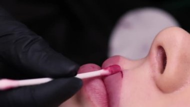 Kalıcı dudak makyaj ustası prosedürü, pamuklu bezle dudaktaki fazlalığı siler. Yüksek kalite 4k görüntü