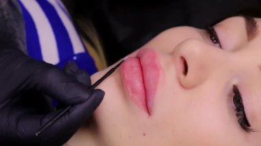 Usta, kalıcı makyajın ilk aşamasından sonra modellerin dudaklarına anestezi uygular. Yüksek kalite 4k görüntü