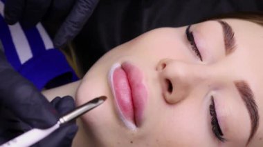 Kalıcı makyaj prosedüründe dolgun dudaklı güzel kız model dudaklarını prosedüre hazırlıyor. Yüksek kalite 4k görüntü
