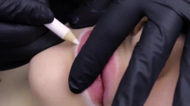 Makyaj ustası için modelin dudak hatlarını hazırlamak bir kalemle dudakların dış hatlarını belirler. Yüksek kalite 4k görüntü