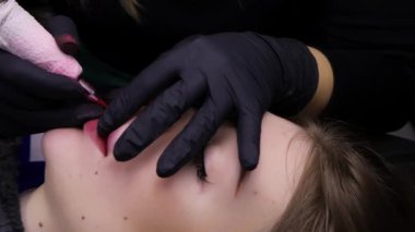 Kamerayı yatay olarak hareket ettirirken, kalıcı makyaj ustası modeli parmaklarıyla tutarken işlemi gerçekleştirir. Yüksek kalite 4k görüntü