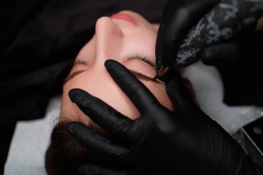 Kalıcı makyaj ustası, modelin kaşlarına kalıcı makyaj uygular. Kaş kalıcı makyaj kozmetik prosedürü.