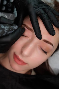 Esmer, kozmetoloji odasında kalıcı makyaj prosedürü üzerine. Kaş kalıcı makyaj kozmetik prosedürü.