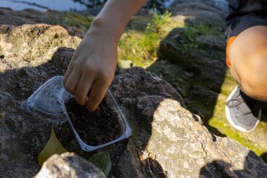 Parmaklarıyla solucanlarla yem yutan bir gencin elleri. Yazın nehirde spor balıkçılığı.