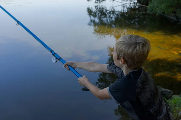 川のティーンエイジャーは魚を捕まえるために釣り糸を投げる 夏の川でのスポーツ釣り — ストック写真