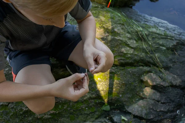 ワームを釣りに使おうとしている10代の若者の手 夏の川でのスポーツ釣り — ストック写真