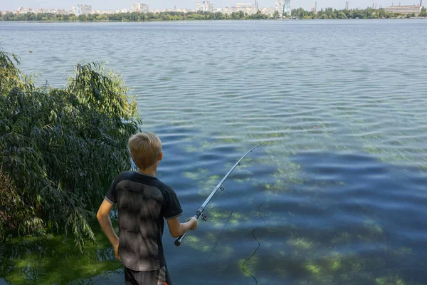 ティーンエイジャーは釣り棒を持ち 魚のニブルを見ています 夏の川でのスポーツ釣り — ストック写真