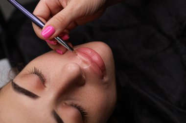 Kalıcı makyaj işleminden önce dudak hatlarına temel uygulanıyor. Sarışınlar için hassas daimi dudak makyajı