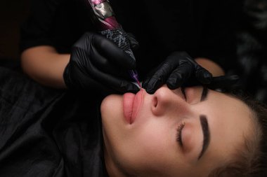 Dudakların kalıcı makyajı prosedürüne yakın çekim yapıldığında, usta kalıcı makyaj uygular. Sarışınlar için hassas daimi dudak makyajı