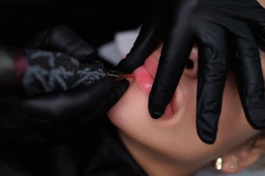 Dudaklar için kalıcı makyaj prosedürü, usta dudakları gerer ve kalıcı makyaj uygular. Sarışınlar için hassas daimi dudak makyajı