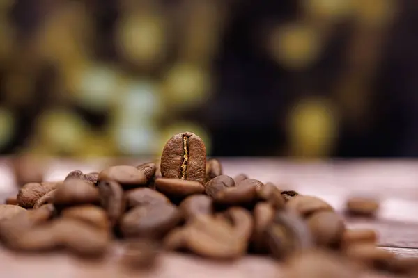 The coffee bean is visible against the pile of coffee beans behind, which creates a nice bokeh.  Coffee beans on the table.