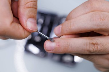 Tırnağı bir aletle kazımak. Bir erkek manikür yaptırır.