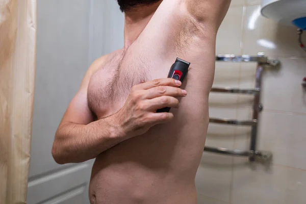 男は電気カミソリで彼の下着の髪を削除する バスルームにスポーツフィギュアを持つ男 — ストック写真