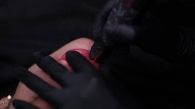 Pigmentlerin tek kullanımlık kartuşlar ve dövme makinesi kullanılarak uygulandığı model dudakların yakın plan görüntüsü. 