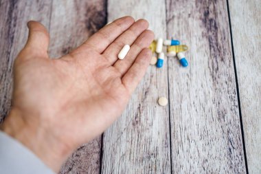 Parmaklarda kapsül, besin takviyeleri ve vitaminler var..