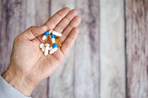 Vitamin capsules in hand, nutritional supplements and vitamins.