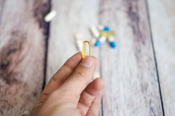 Fingers holding an omega capsule. nutritional supplements and vitamins.