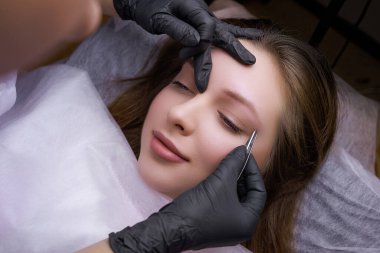 Kalıcı makyajdan önce üstadın kaşlarını cımbızla düzelttiği modelin üst görüntüsü. PMU Prosedürü, Kalıcı Kaş Makyajı.