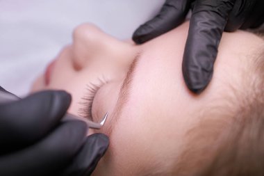 Cımbızla kaş düzeltmenin makro fotoğrafı. PMU Prosedürü, Kalıcı Kaş Makyajı.