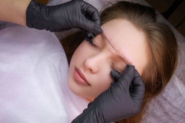 Kalıcı makyaj işleminden önce üstadın işaretlemeyi bir iplikle yaptığı modelin üst görünümü. PMU Prosedürü, Kalıcı Kaş Makyajı.