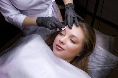 Kaşların yüzeyini pamuklu bir süngerle kaynatmaya yakın çekim. PMU Prosedürü, Kalıcı Kaş Makyajı.