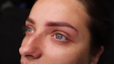 Kalıcı kaş makyajcısı kameranın önünde poz verdikten sonra iş yapmış. Açık renk kaş makyajı, kaş dövmesi.