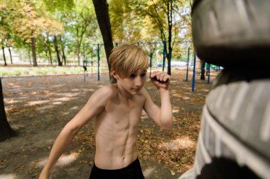 Bir genç, kendini savunma dövüş sanatları pratik yaparken el vuruşu yapar. Parkta spor yapan genç bir çocuk. 